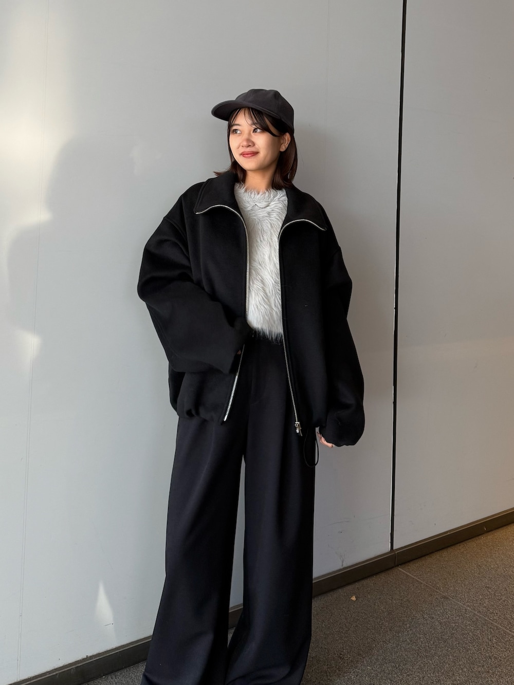 ブラック系のブルゾン、ブラック系のスラックス、グレー系のニット/セーターを着用したレディースの冬コーディネートの3枚目の写真