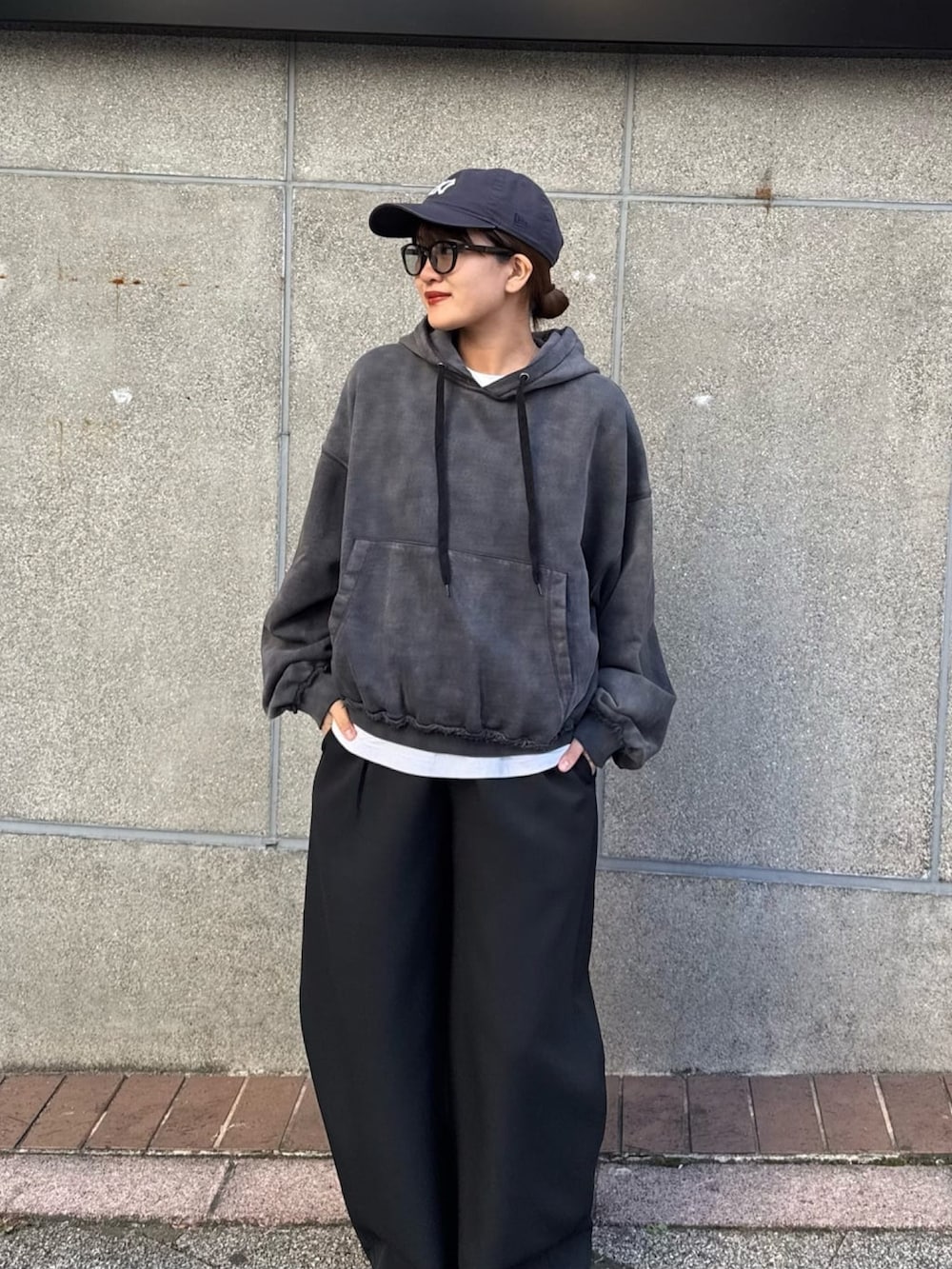 ブラック系のパーカー、ブラック系のスラックス、ブラック系のサングラスを着用したレディースの冬コーディネートの2枚目の写真