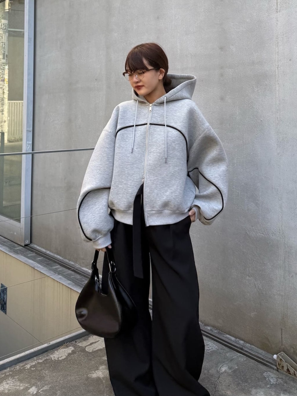 グレー系のパーカー、ブラック系のスラックス、ブラック系のハンドバッグを着用したレディースの冬コーディネートの4枚目の写真