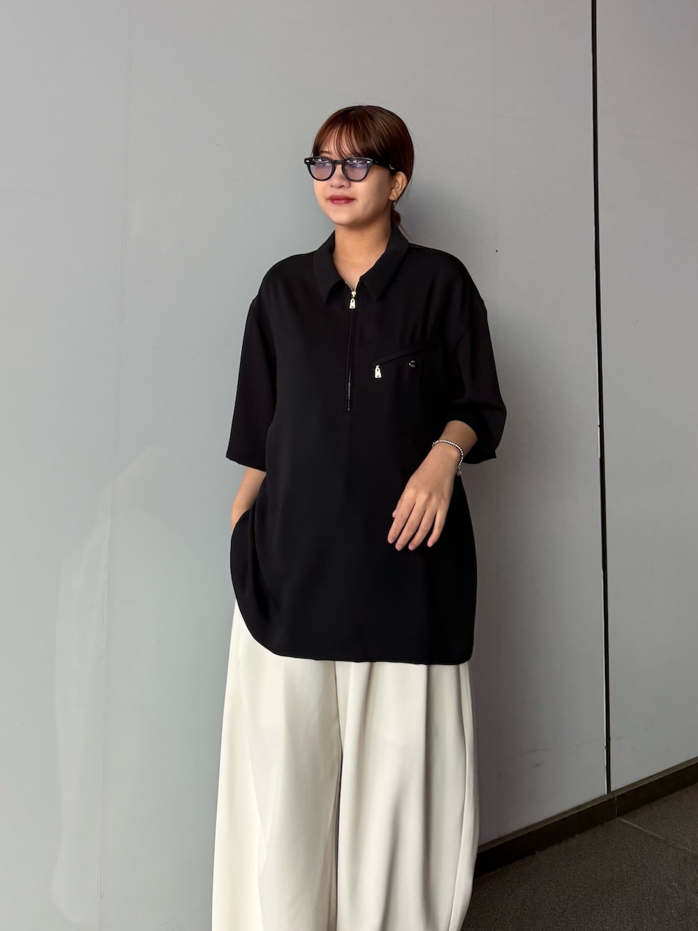 グレー系のスラックス、ブラック系のポロシャツを着用したレディースの春コーディネートの4枚目の写真