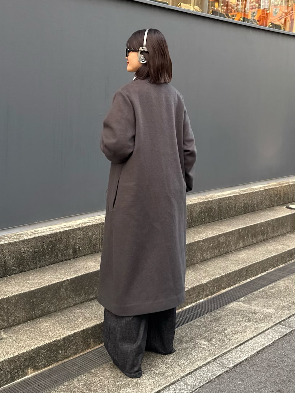 グレー系のチェスターコート、ホワイト系のニット/セーター、ブラック系のデニムパンツを着用したレディースの秋コーディネートの4枚目の写真