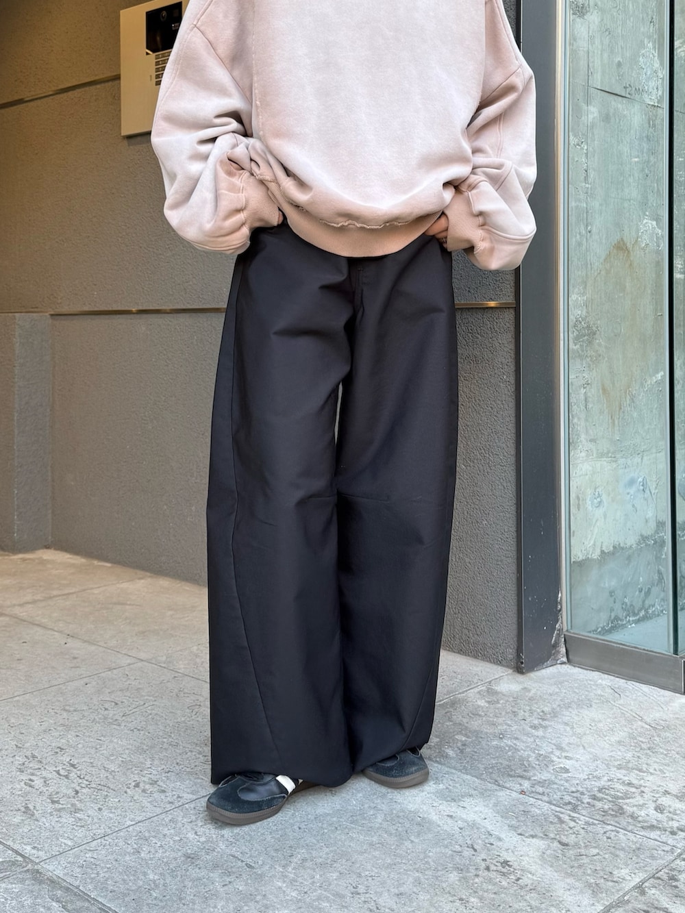 ベージュ系のスウェット、ブラック系のスラックス、ブラック系のサングラスを着用したレディースの冬コーディネートの8枚目の写真