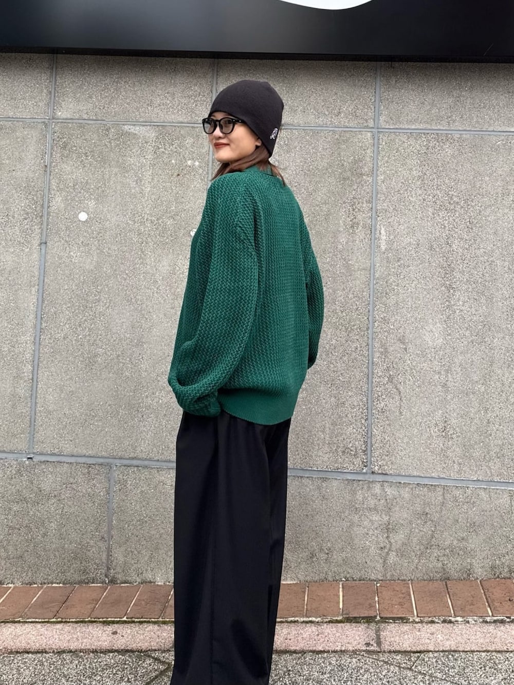 グリーン系のニット/セーター、グレー系のスラックスを着用したレディースの冬コーディネートの6枚目の写真