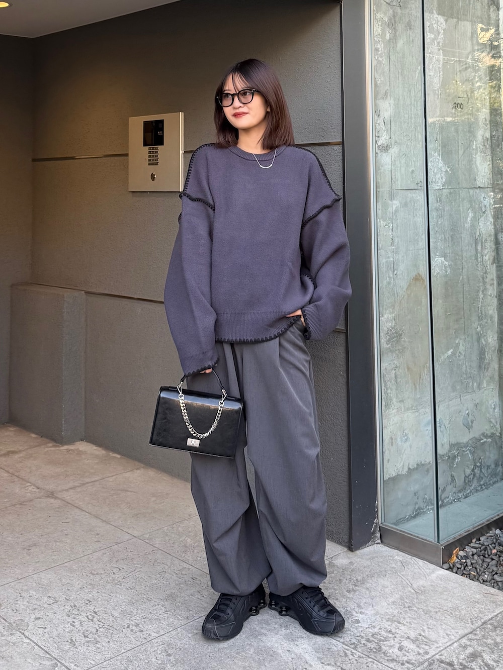 グレー系のニット/セーター、グレー系のスラックス、ブラック系のショルダーバッグを着用したレディースの冬コーディネートの3枚目の写真