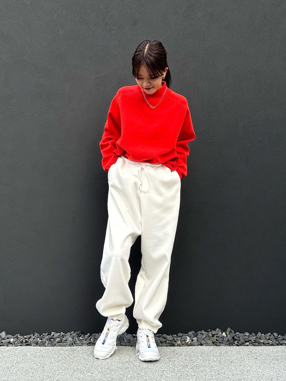 ホワイト系のスウェットパンツ、オレンジ系のニット/セーター、ホワイト系のスニーカーを着用したレディースの秋コーディネートの4枚目の写真