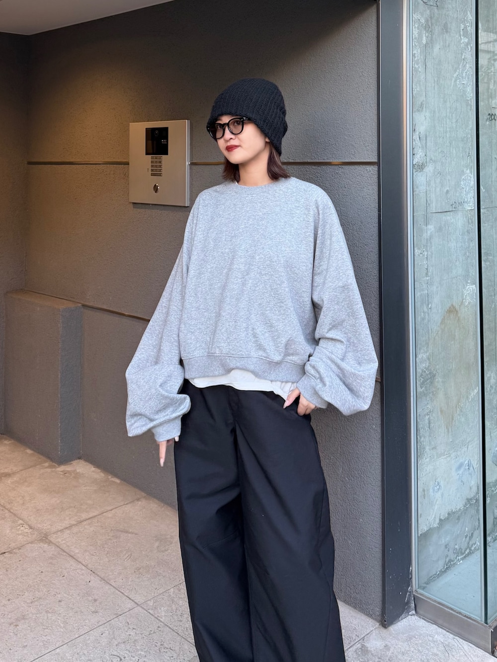 グレー系のスウェット、ブラック系のスラックス、ブラック系のサングラスを着用したレディースの冬コーディネートの2枚目の写真