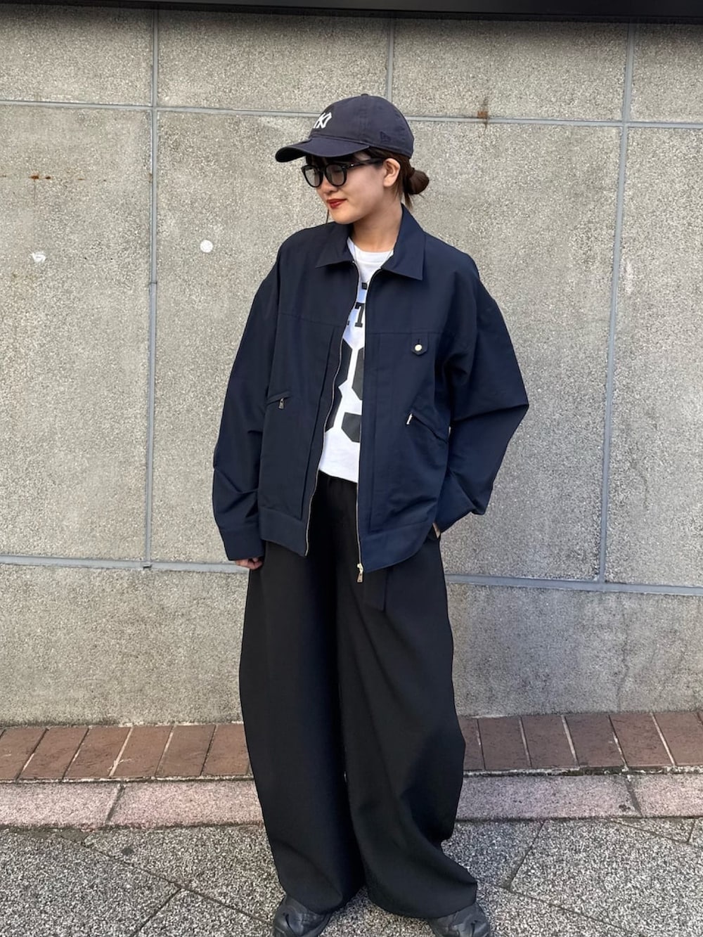 ブラック系のスラックス、ブルー系のブルゾン、ブラック系のサングラスを着用したレディースの冬コーディネートの5枚目の写真