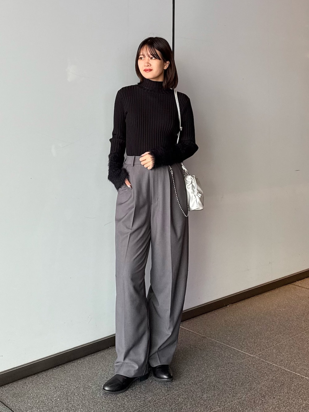 グレー系のスラックス、シルバー系のショルダーバッグ、ブラック系のTシャツ/カットソーを着用したレディースの秋コーディネートの2枚目の写真