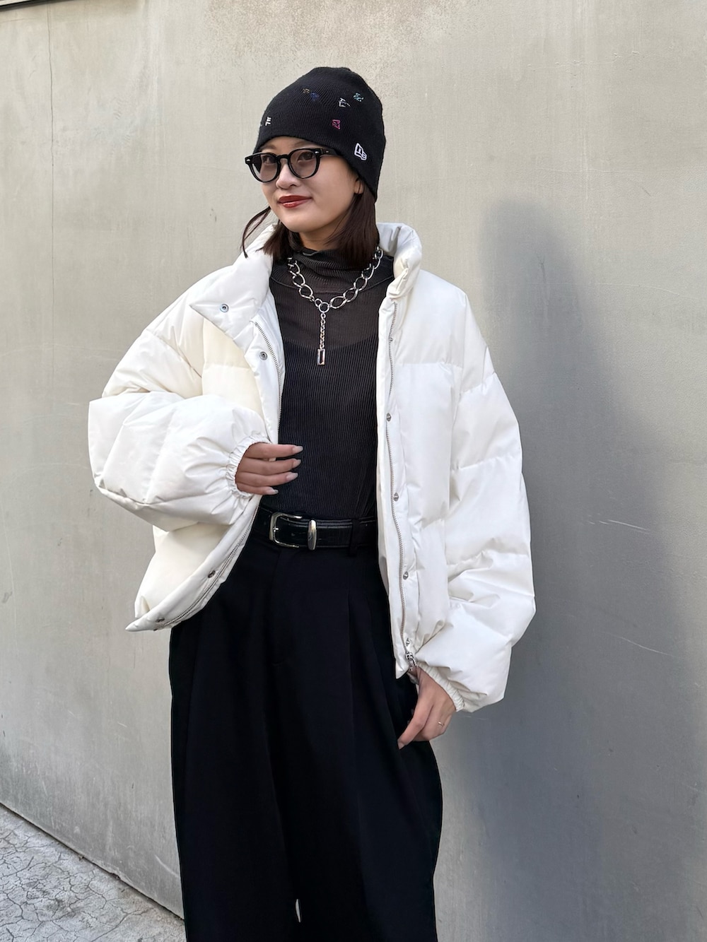ホワイト系のダウンジャケット/コート、ブラック系のスラックス、ブラック系のベルトを着用したレディースの秋コーディネートの7枚目の写真