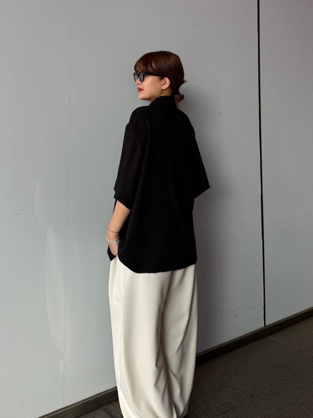 グレー系のスラックス、ブラック系のポロシャツを着用したレディースの春コーディネートの6枚目の写真