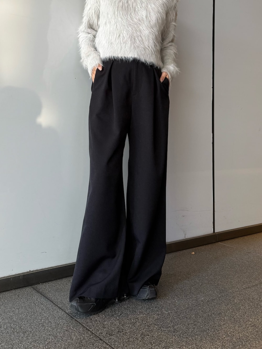 グレー系のニット/セーター、ブラック系のチェスターコート、ブラック系のスラックスを着用したレディースの冬コーディネートの5枚目の写真