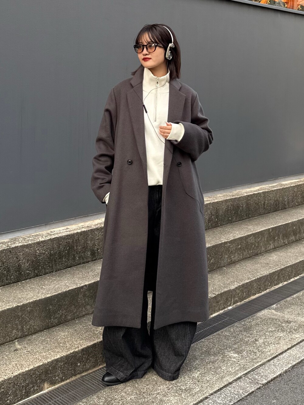 グレー系のチェスターコート、ホワイト系のニット/セーター、ブラック系のデニムパンツを着用したレディースの秋コーディネートの2枚目の写真