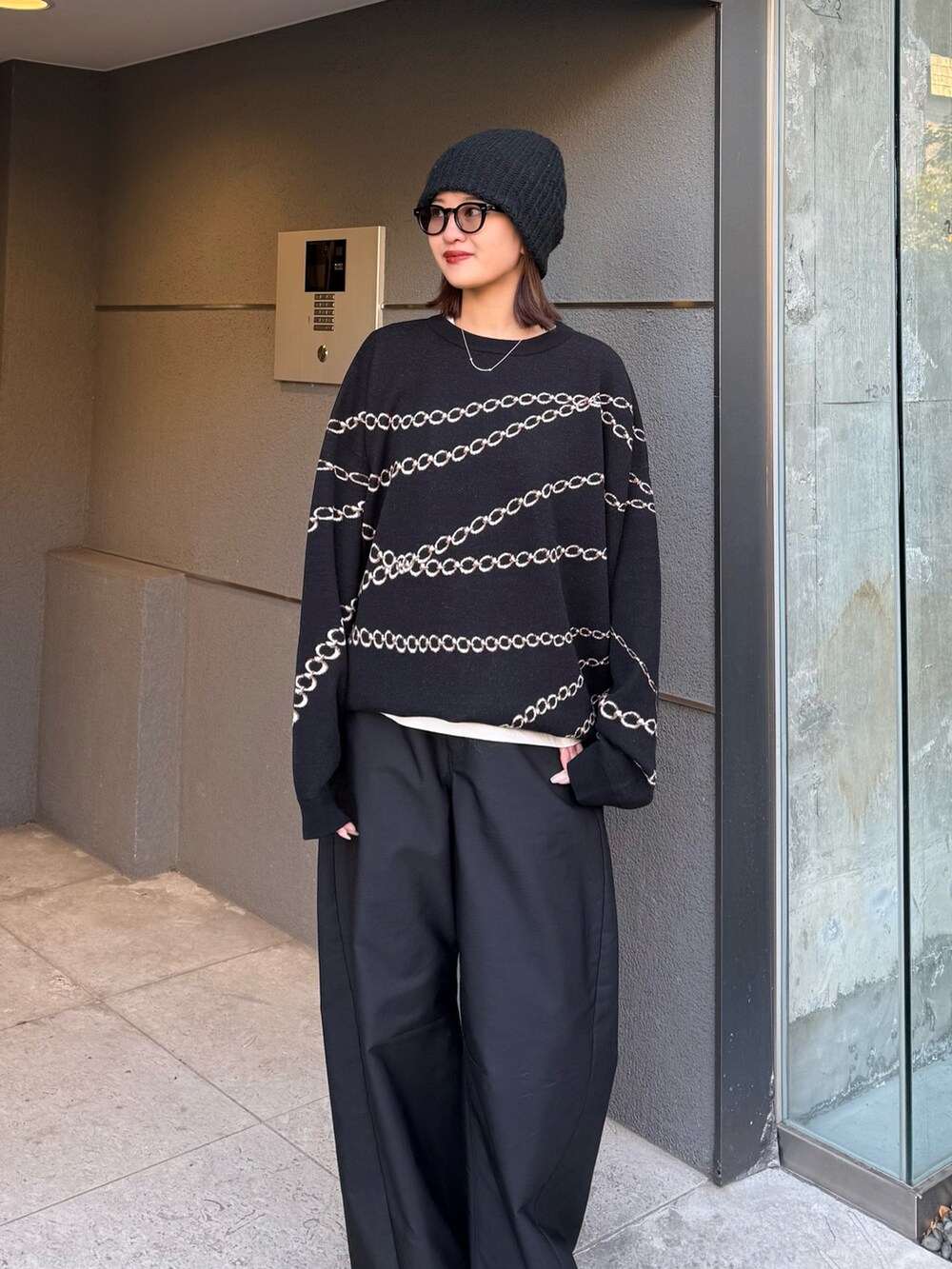 ブラック系のスラックス、ブラック系のニット/セーター、ブラック系のサングラスを着用したレディースの冬コーディネートの6枚目の写真