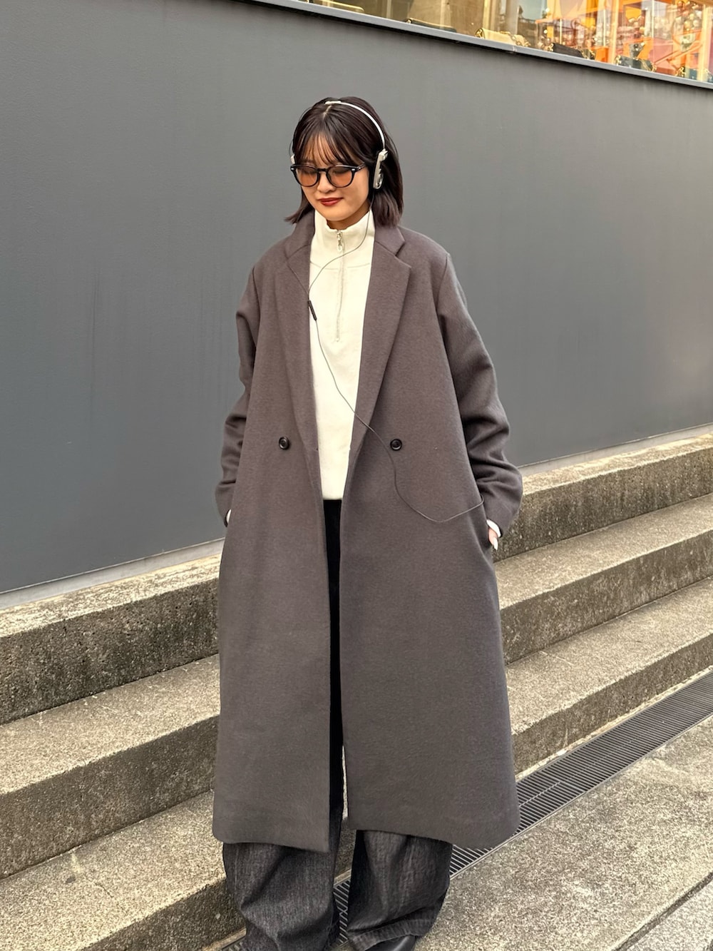 グレー系のチェスターコート、ホワイト系のニット/セーター、ブラック系のデニムパンツを着用したレディースの秋コーディネートの5枚目の写真