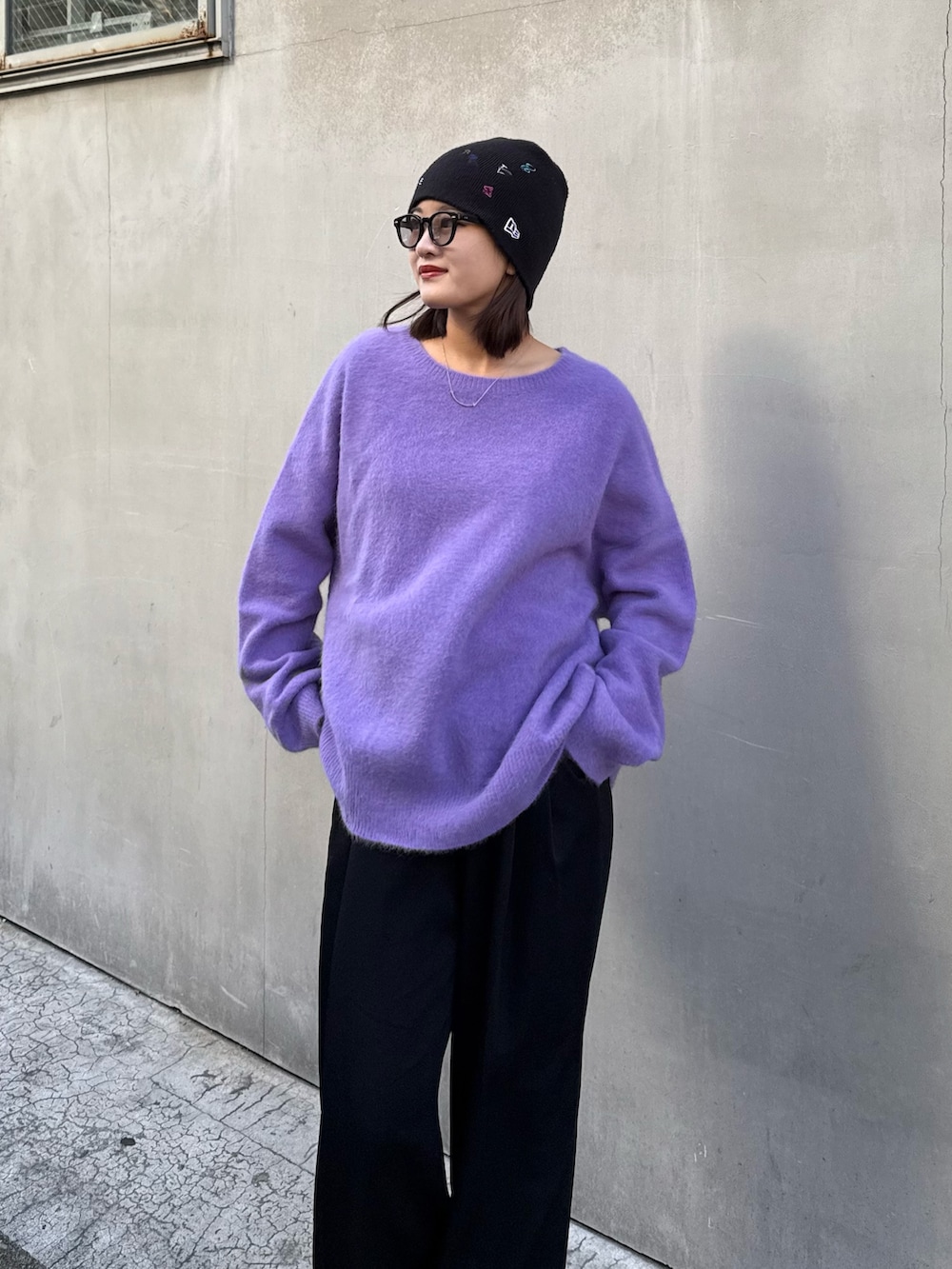 パープル系のニット/セーター、ブラック系のスラックス、ブラック系のサングラスを着用したレディースの秋コーディネートの5枚目の写真
