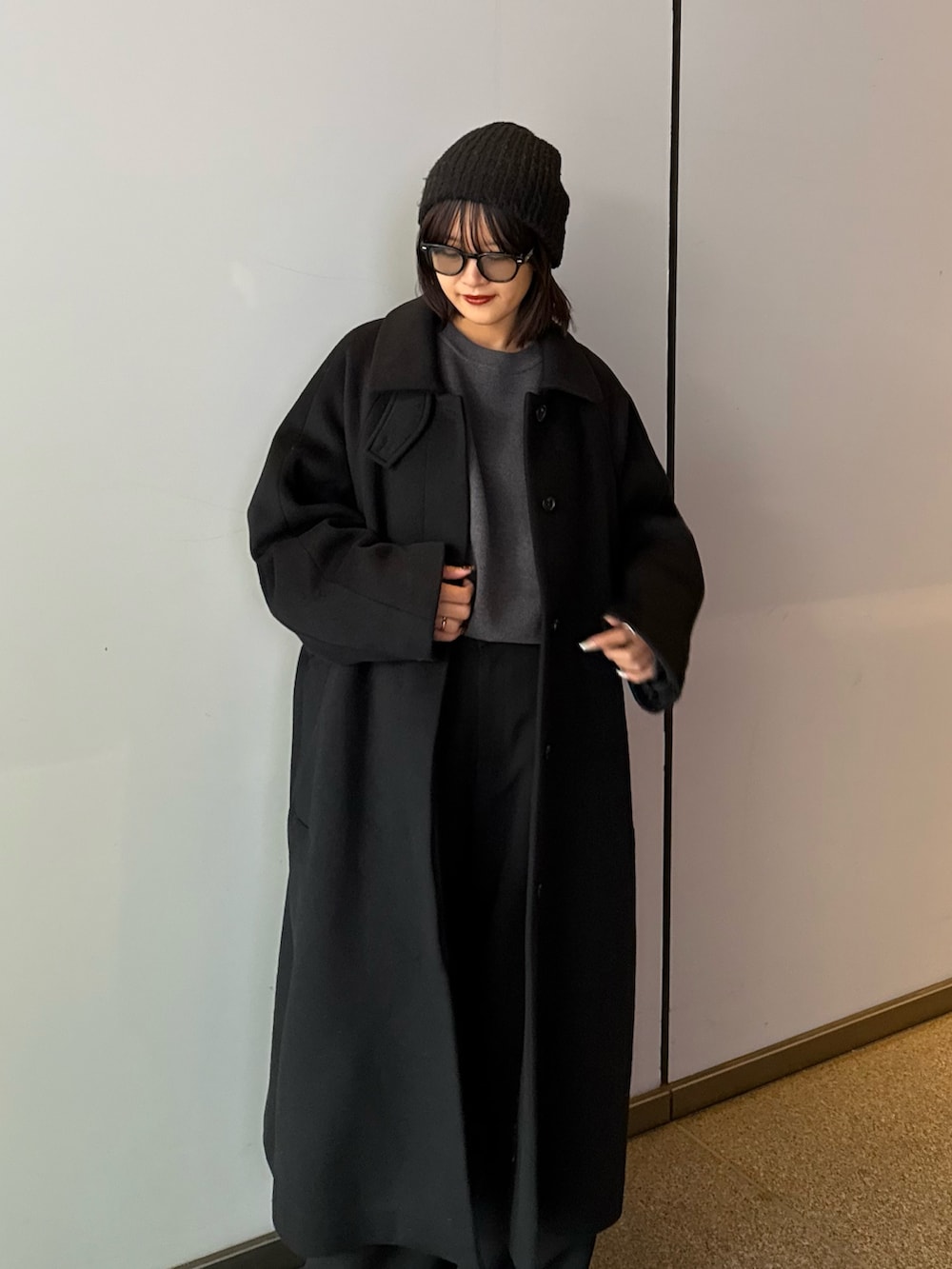 ブラック系のステンカラーコート、ブラック系のステンカラーコート、グレー系のニット/セーターを着用したレディースの秋コーディネートの3枚目の写真