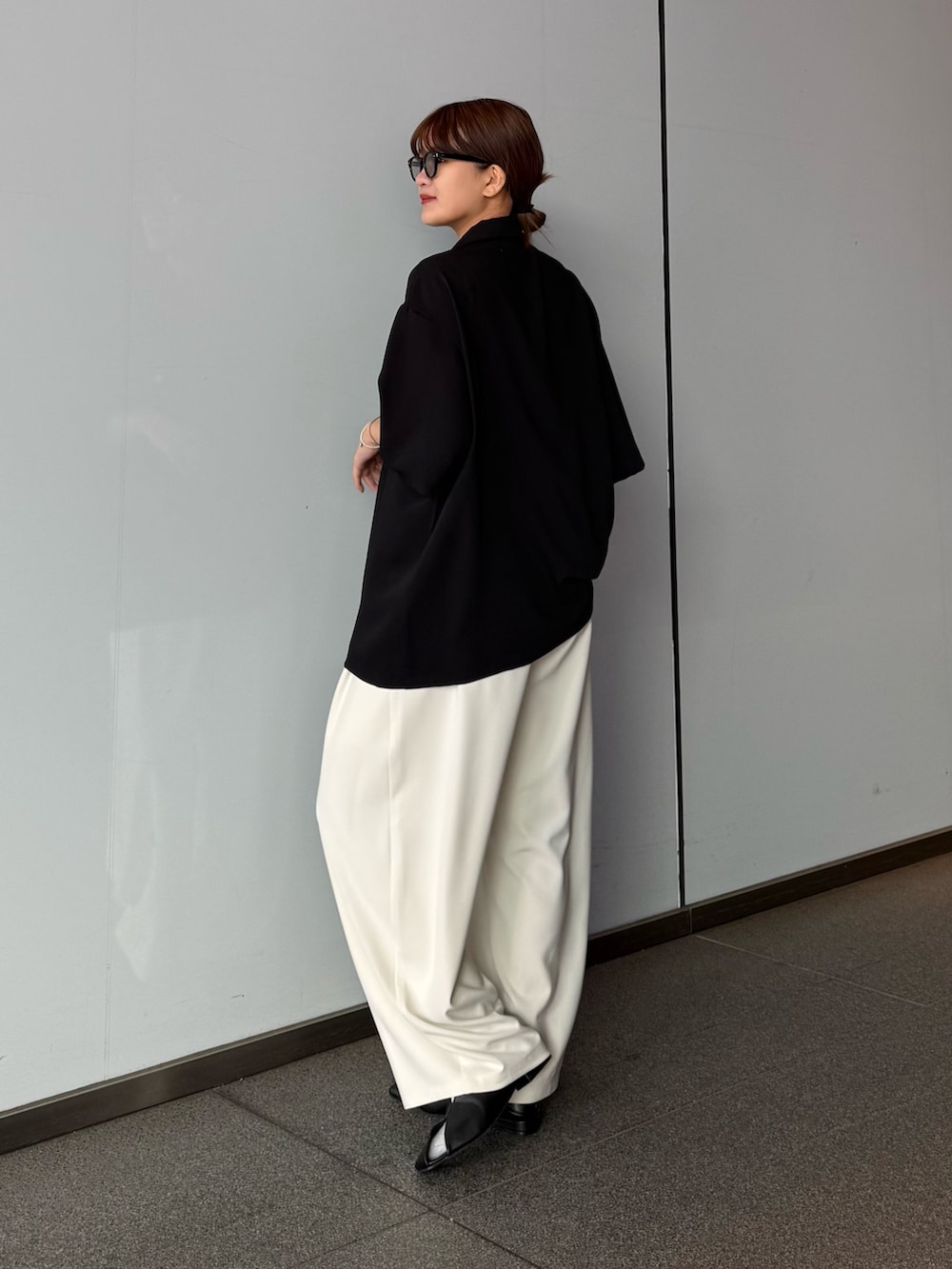 グレー系のスラックス、ブラック系のポロシャツを着用したレディースの春コーディネートの3枚目の写真