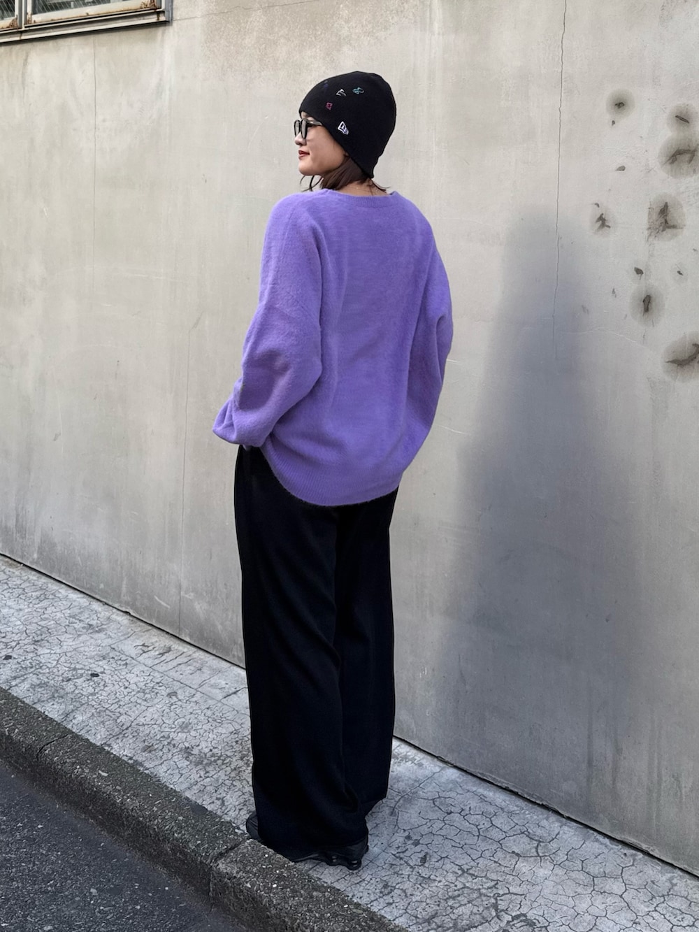 パープル系のニット/セーター、ブラック系のスラックス、ブラック系のサングラスを着用したレディースの秋コーディネートの4枚目の写真