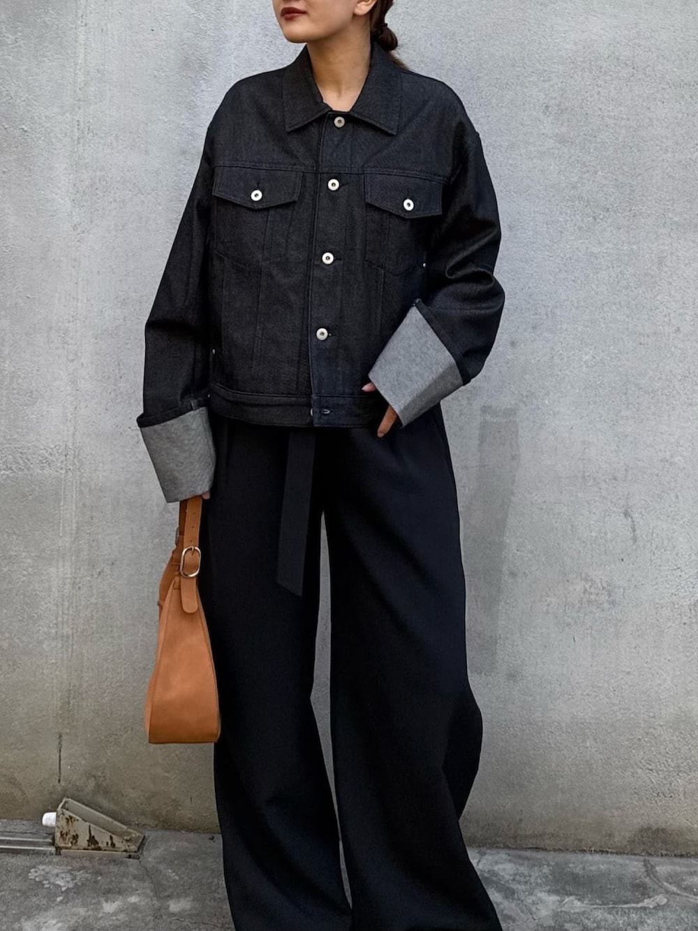 ブラック系のデニムジャケット、ブラック系のスラックス、ブラック系のハンドバッグを着用したレディースの冬コーディネートの4枚目の写真