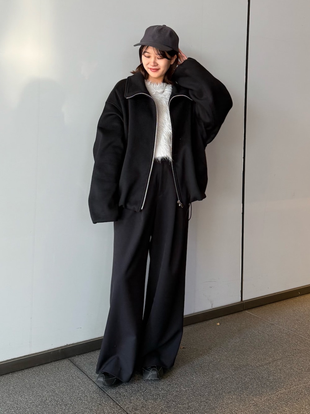 ブラック系のブルゾン、ブラック系のスラックス、グレー系のニット/セーターを着用したレディースの冬コーディネートの4枚目の写真