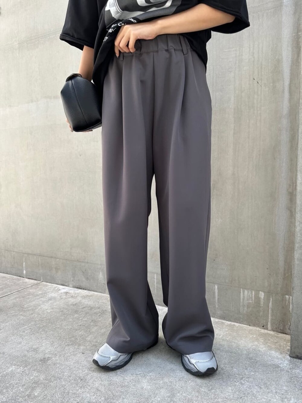 グレー系のパンツ、ブラック系のTシャツ/カットソー、ブラック系のバッグを着用したレディースの夏コーディネートの2枚目の写真