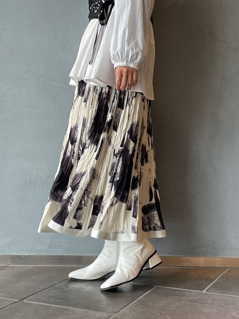 ブラック系のシャツ/ブラウス、ホワイト系のスカート、ホワイト系のブーツを着用したレディースの春コーディネートの5枚目の写真