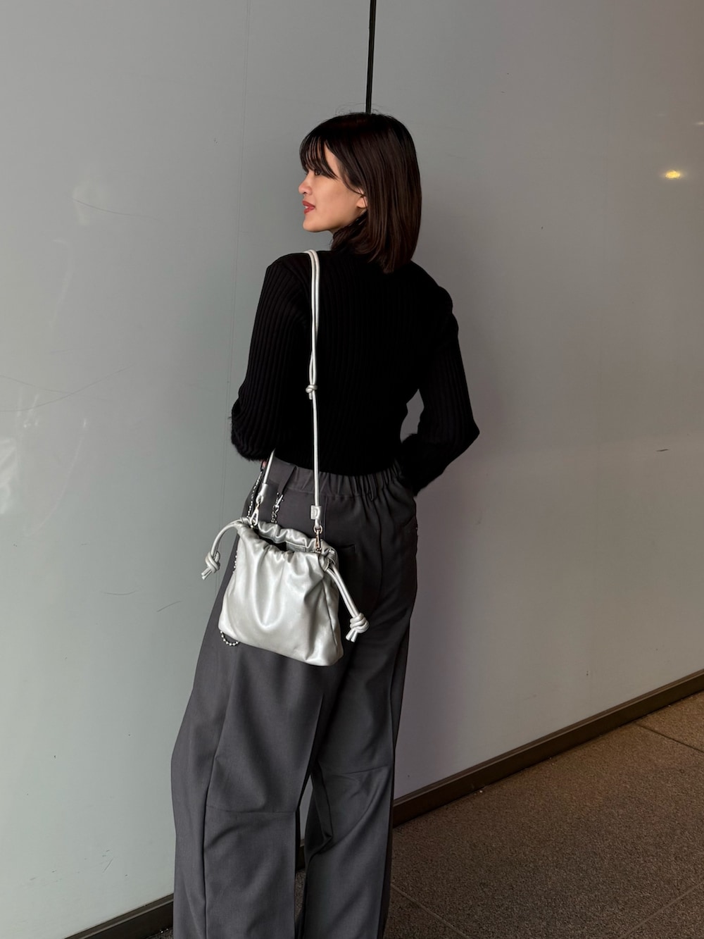グレー系のスラックス、シルバー系のショルダーバッグ、ブラック系のTシャツ/カットソーを着用したレディースの秋コーディネートの6枚目の写真