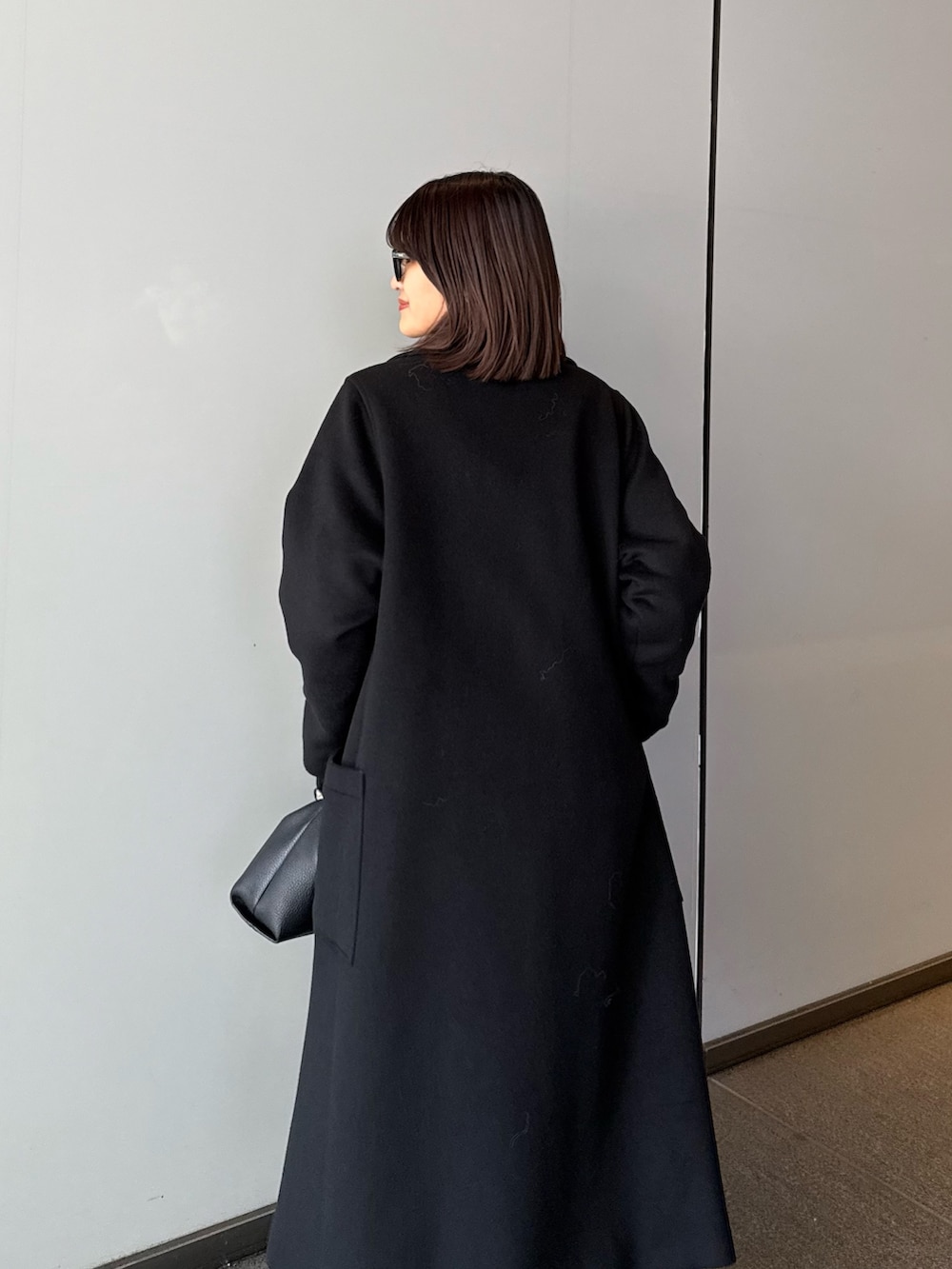 ブラック系のチェスターコート、ブラック系のニット/セーター、ブラック系のトートバッグを着用したレディースの秋コーディネートの7枚目の写真