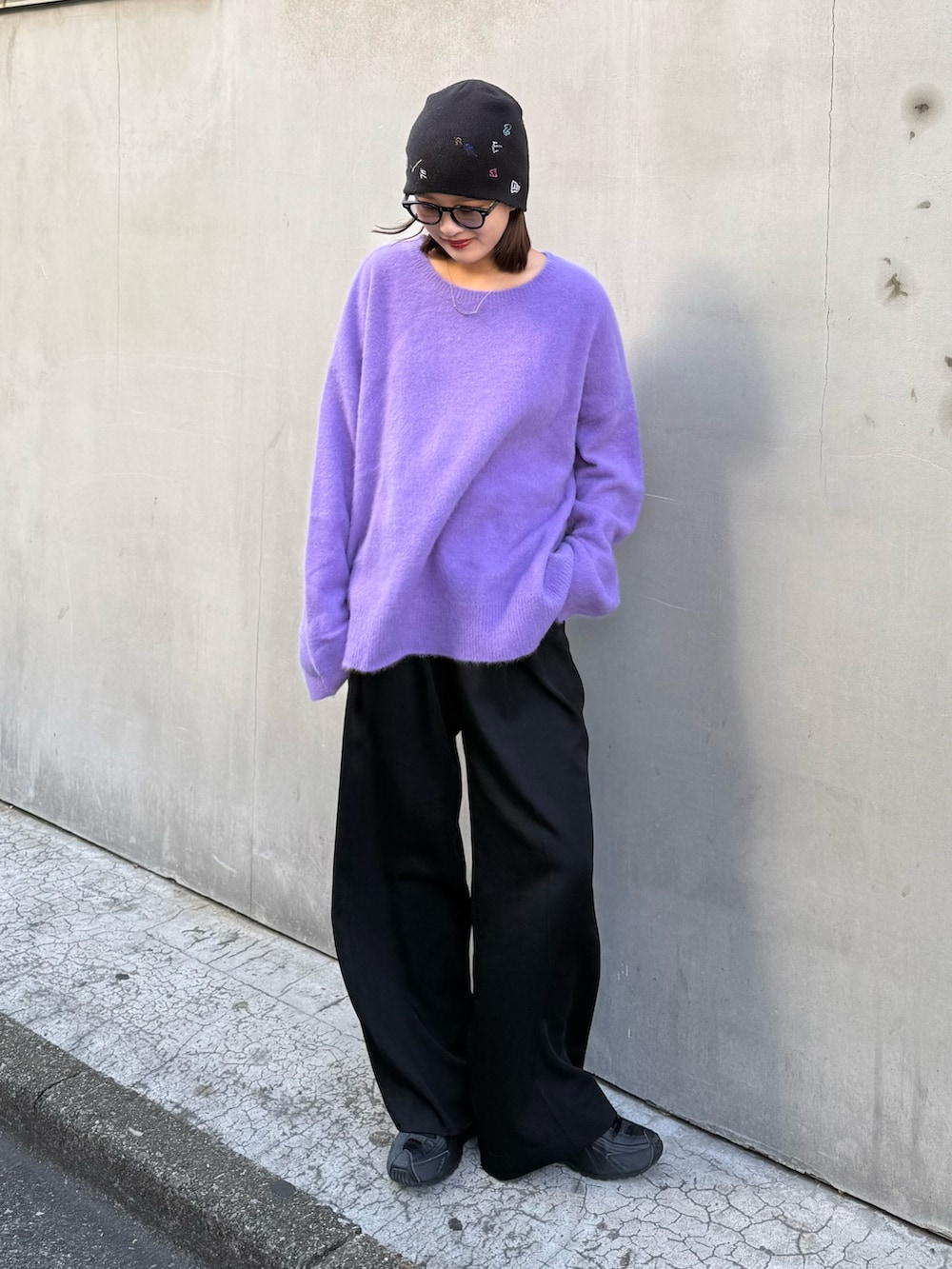 パープル系のニット/セーター、ブラック系のスラックス、ブラック系のサングラスを着用したレディースの秋コーディネートの2枚目の写真