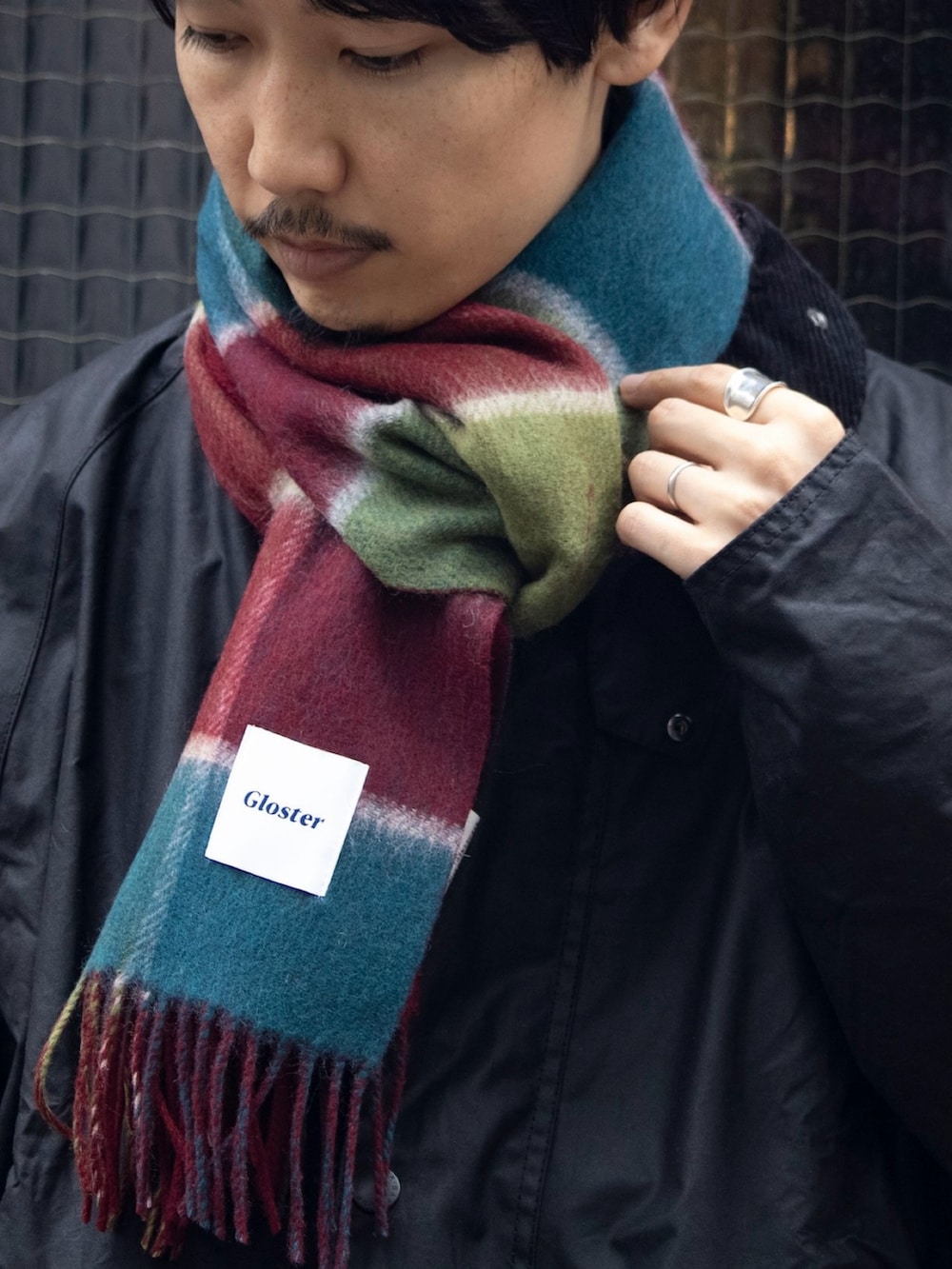 ブラック系のブルゾン、グリーン系のニット/セーター、ブルー系のデニムパンツを着用したメンズの秋コーディネートの2枚目の写真