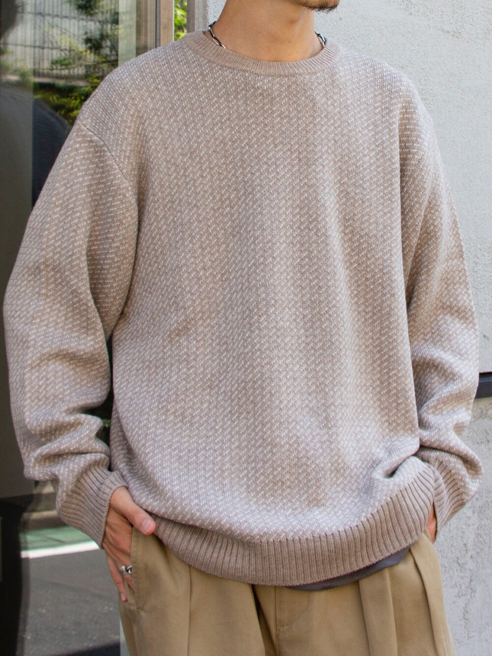 ベージュ系のニット/セーター、ベージュ系のチノパンツを着用したメンズの夏コーディネートの2枚目の写真