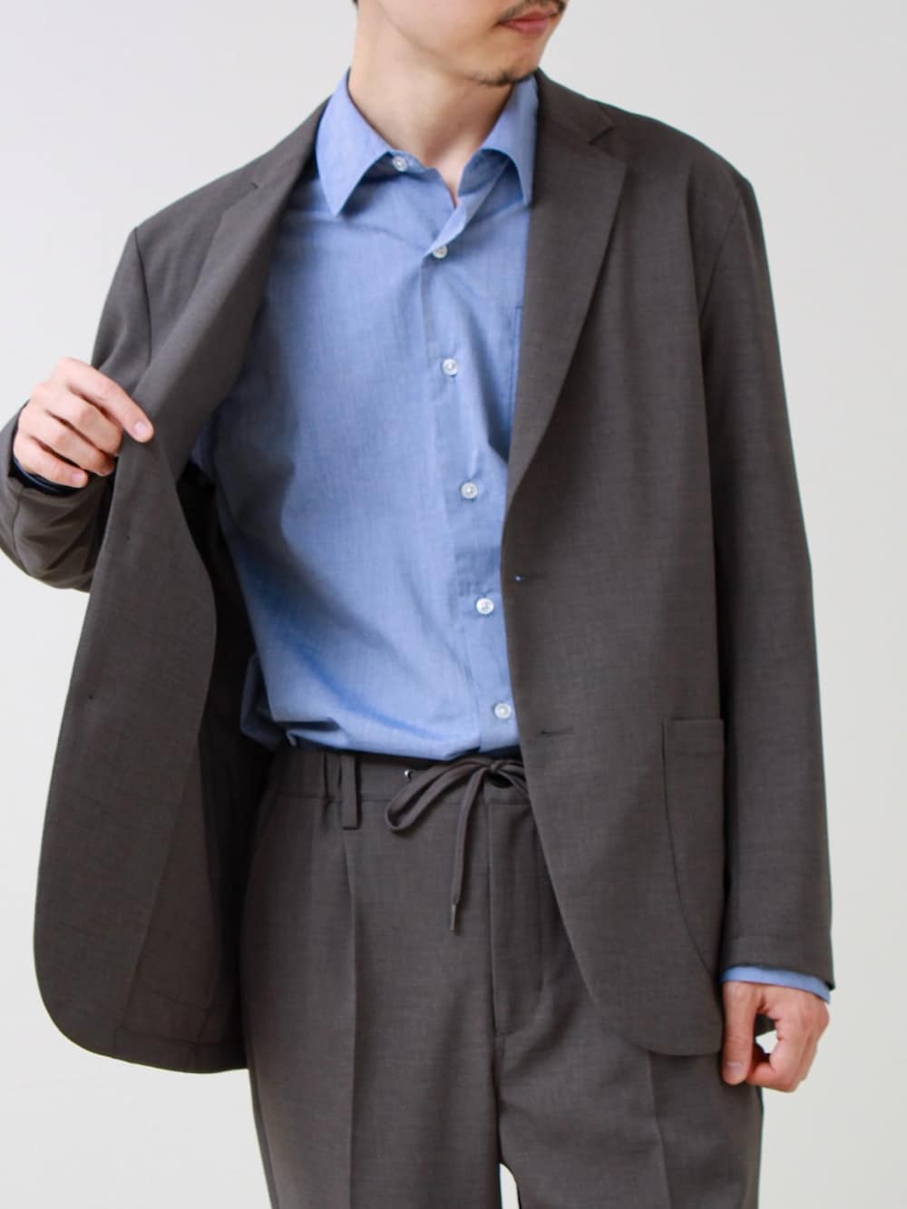 グレー系のテーラードジャケット、ブルー系のシャツ/ブラウス、グレー系のその他パンツを着用したメンズの春コーディネートの3枚目の写真