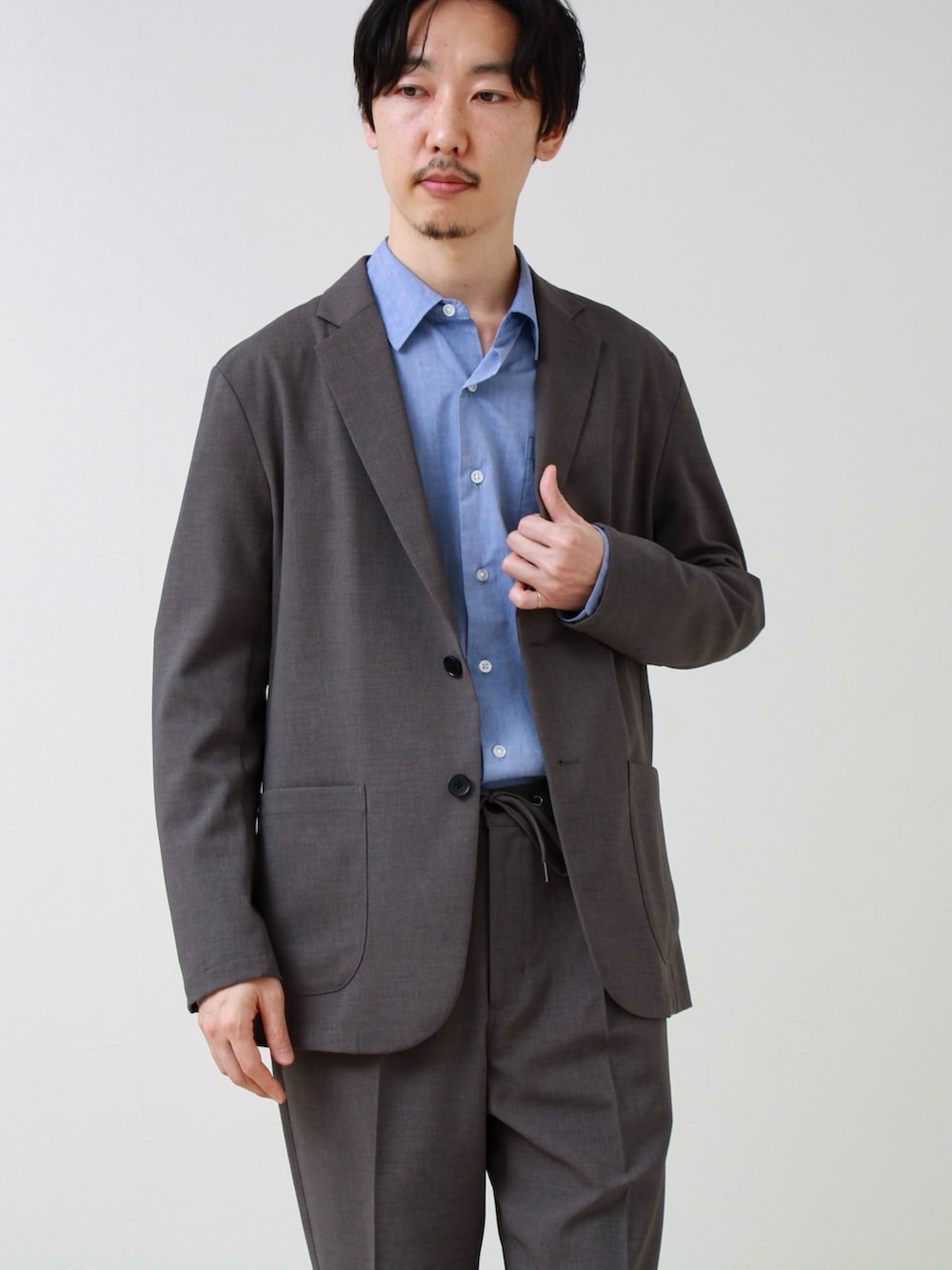 グレー系のテーラードジャケット、ブルー系のシャツ/ブラウス、グレー系のその他パンツを着用したメンズの春コーディネートの2枚目の写真