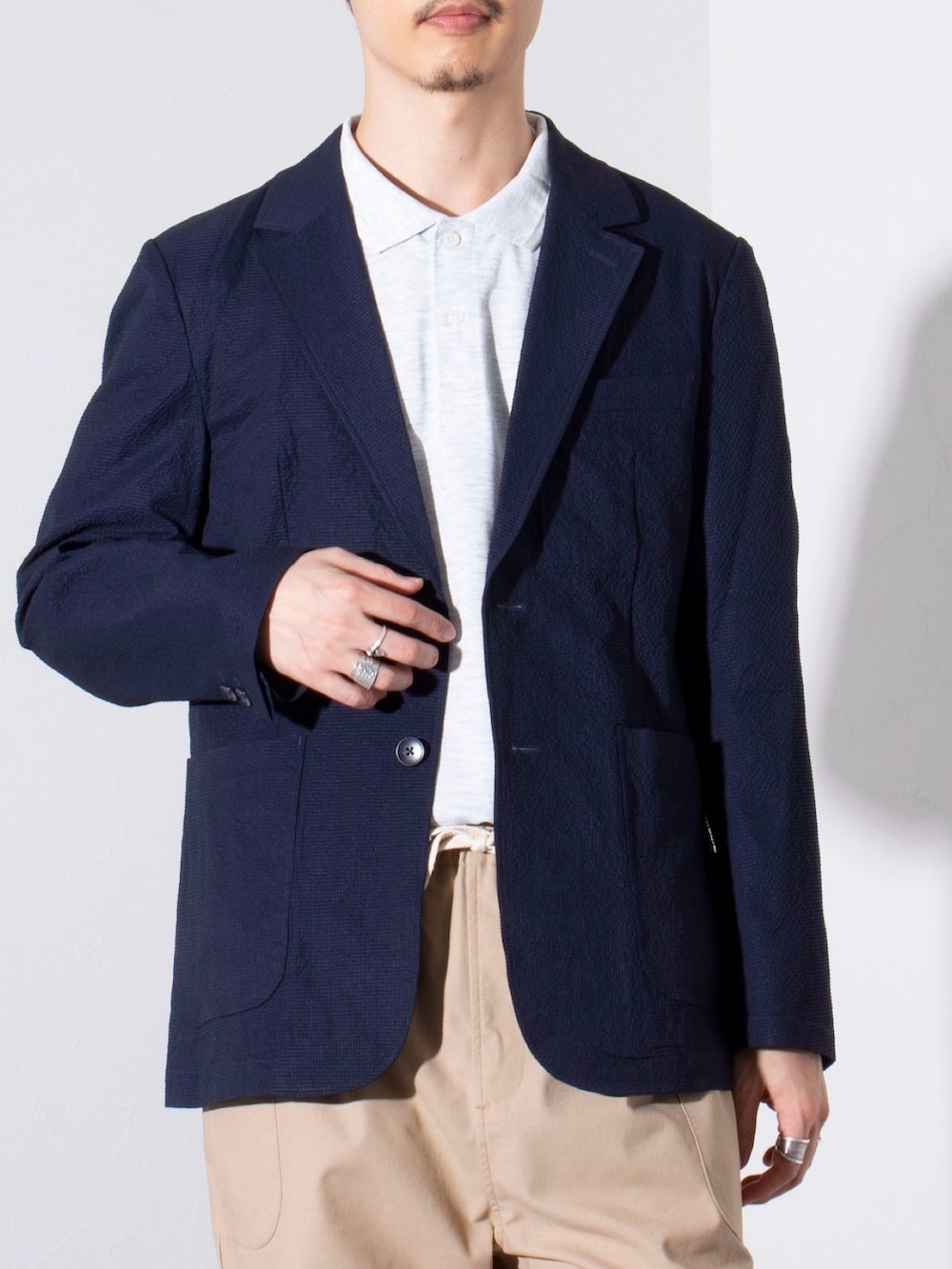 ブルー系のテーラードジャケット、グレー系のポロシャツ、ベージュ系のその他パンツを着用したメンズの春コーディネートの2枚目の写真