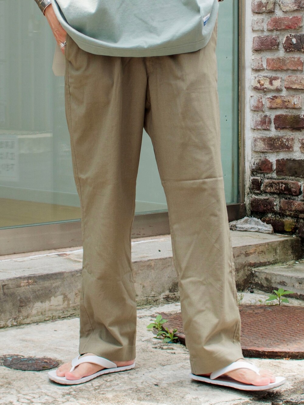 グレー系のTシャツ/カットソー、ベージュ系のその他パンツ、ホワイト系のサンダルを着用したメンズの夏コーディネートの4枚目の写真