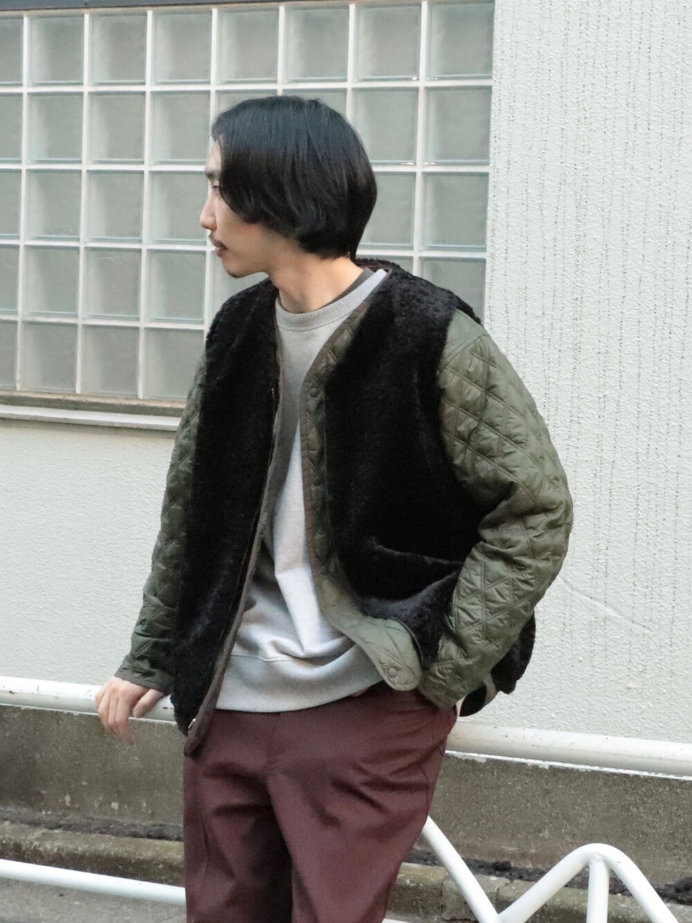 グリーン系のブルゾン、ブラック系のベスト、グレー系のスウェットを着用したメンズの冬コーディネートの3枚目の写真