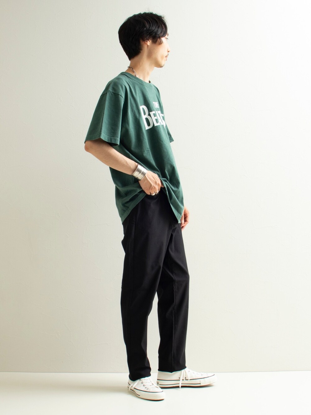 グリーン系のTシャツ/カットソー、ブラック系のパンツ、ホワイト系のスニーカーを着用したメンズの夏コーディネートの2枚目の写真