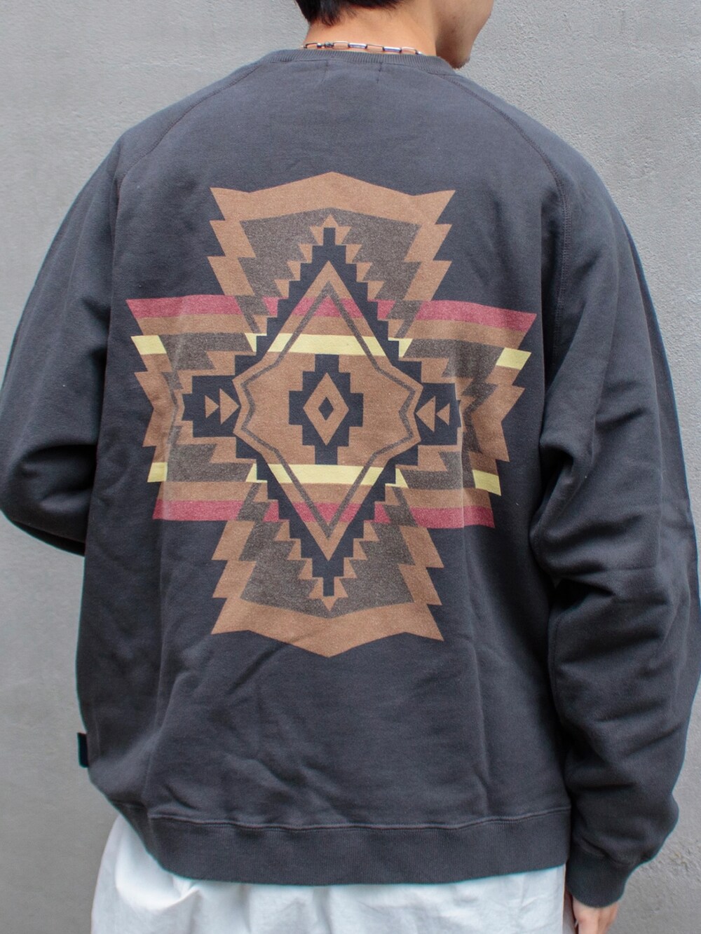 オレンジ系のベスト、グレー系のスウェット、ベージュ系のサンダルを着用したメンズの秋コーディネートの4枚目の写真