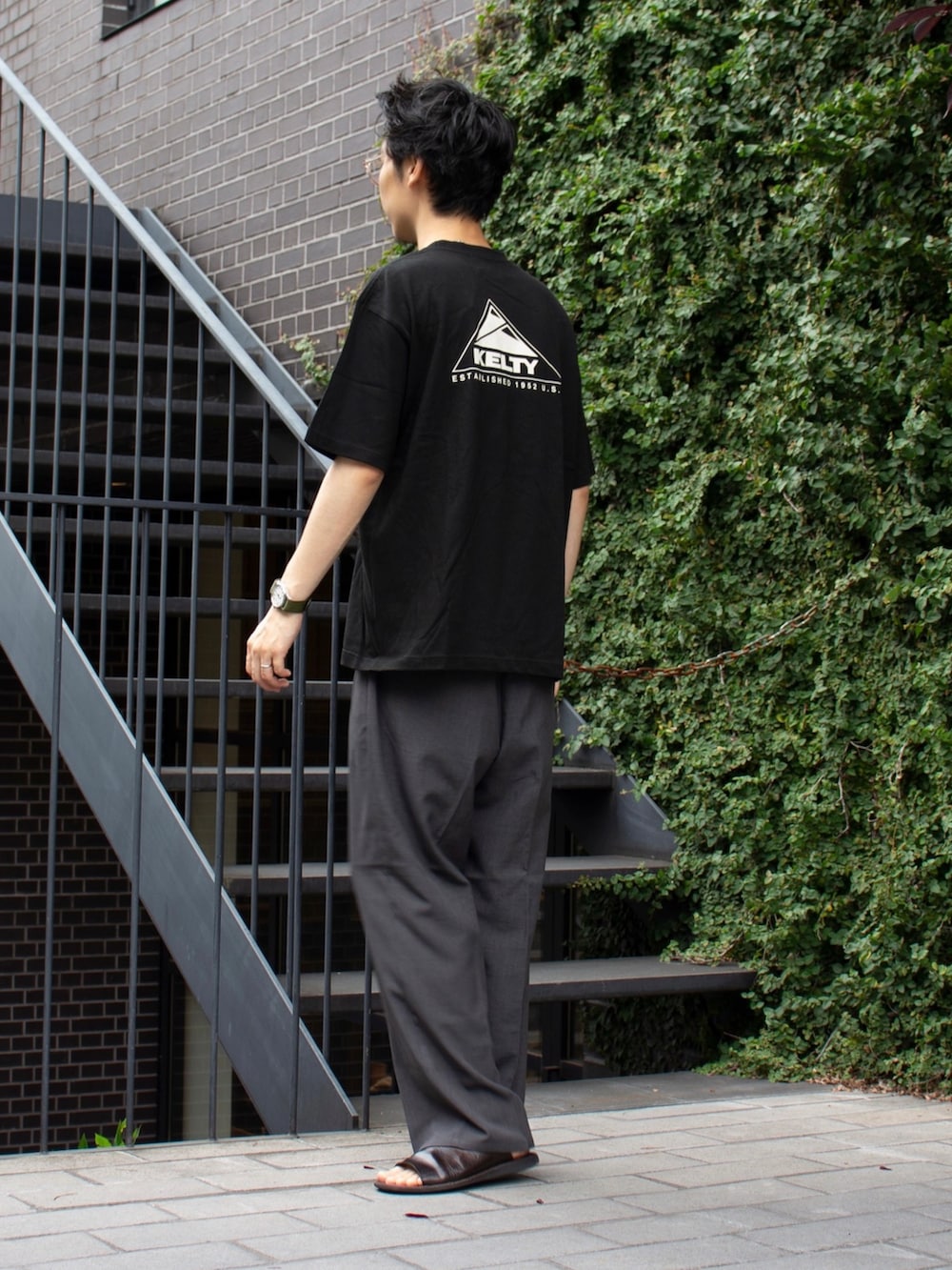 ブラック系のTシャツ/カットソー、グレー系のスラックス、ブラック系のTシャツ/カットソーを着用したメンズの夏コーディネートの2枚目の写真