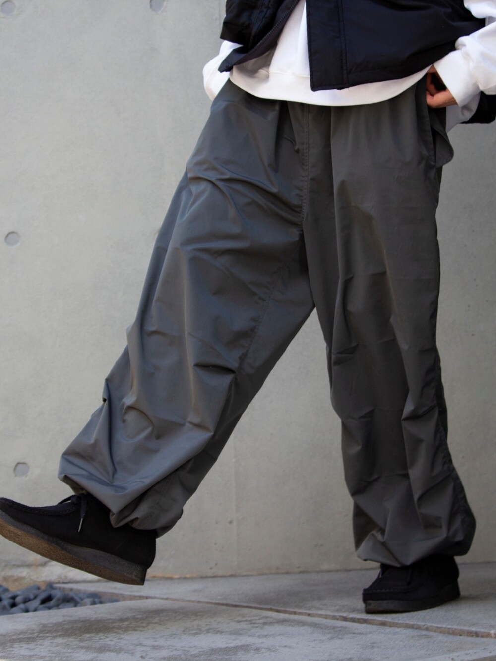 ブラック系のショルダーバッグ、ブラック系のベスト、ホワイト系のスウェットを着用したメンズの冬コーディネートの3枚目の写真