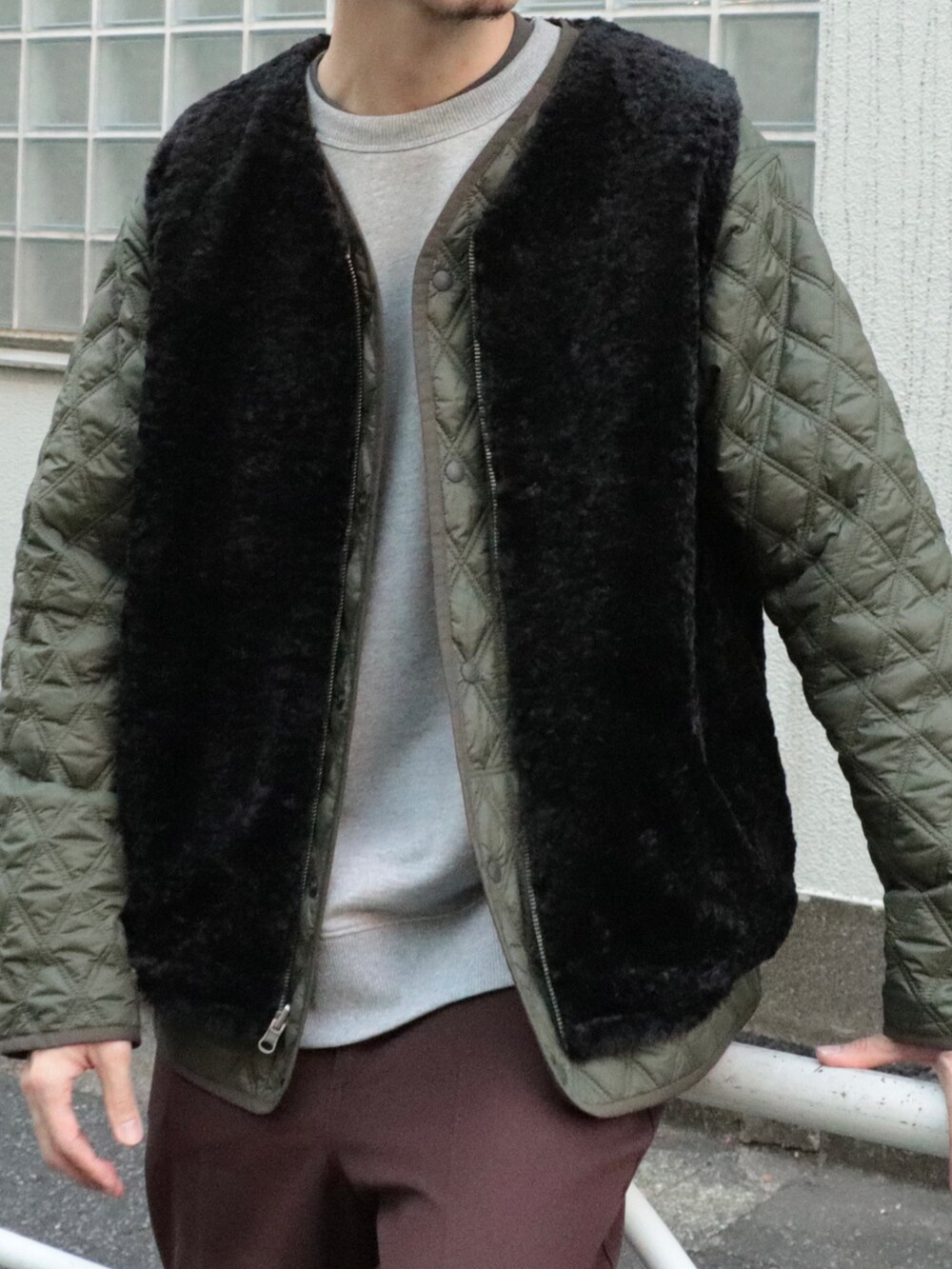 グリーン系のブルゾン、ブラック系のベスト、グレー系のスウェットを着用したメンズの冬コーディネートの2枚目の写真