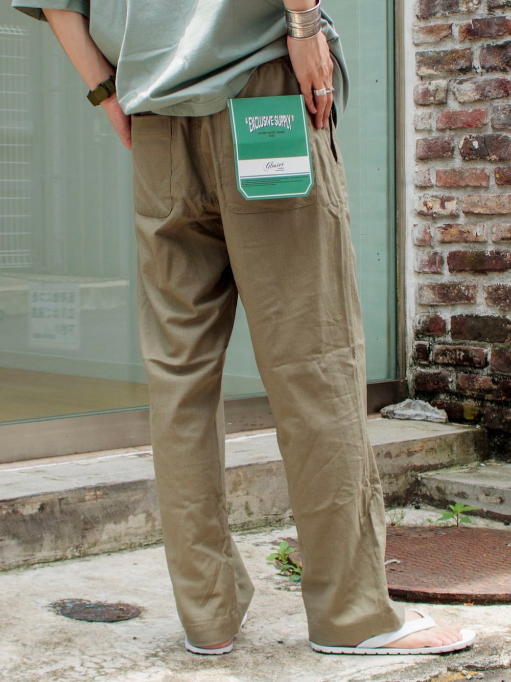 グレー系のTシャツ/カットソー、ベージュ系のその他パンツ、ホワイト系のサンダルを着用したメンズの夏コーディネートの5枚目の写真