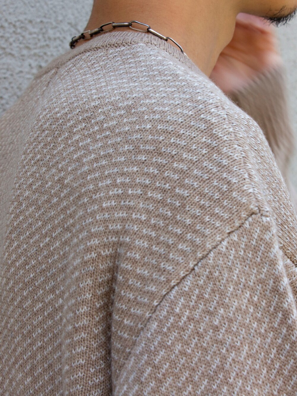 ベージュ系のニット/セーター、ベージュ系のチノパンツを着用したメンズの夏コーディネートの3枚目の写真