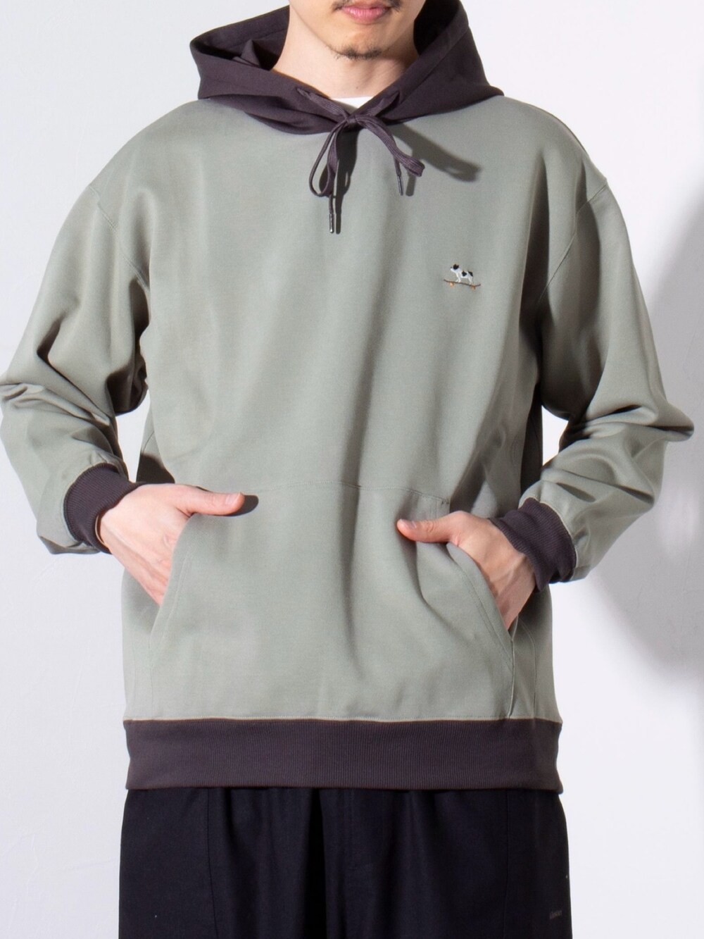 グリーン系のパーカー、ブラック系のその他パンツを着用したメンズの春コーディネートの2枚目の写真