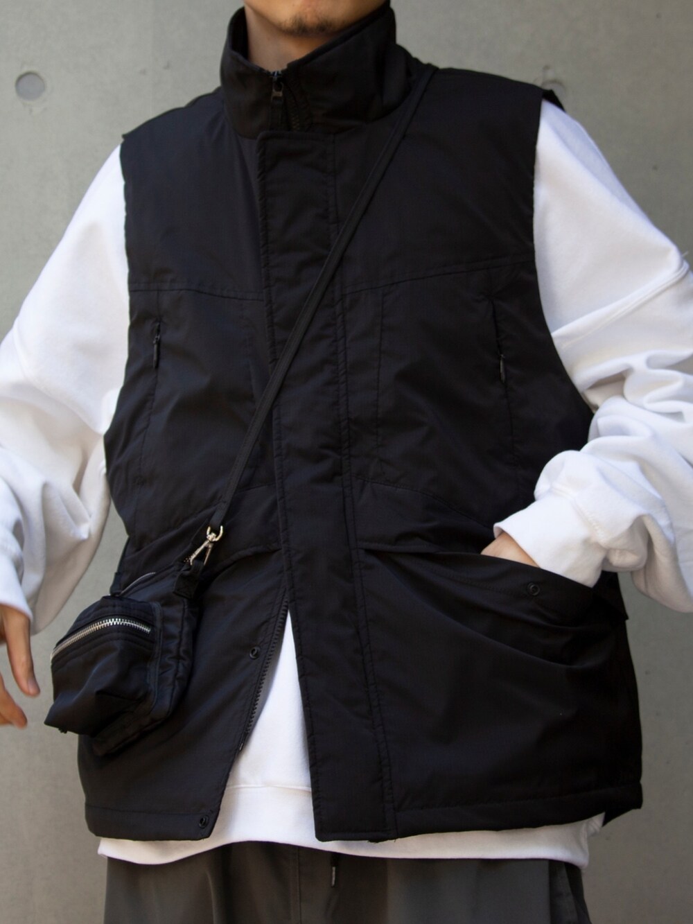 ブラック系のショルダーバッグ、ブラック系のベスト、ホワイト系のスウェットを着用したメンズの冬コーディネートの4枚目の写真