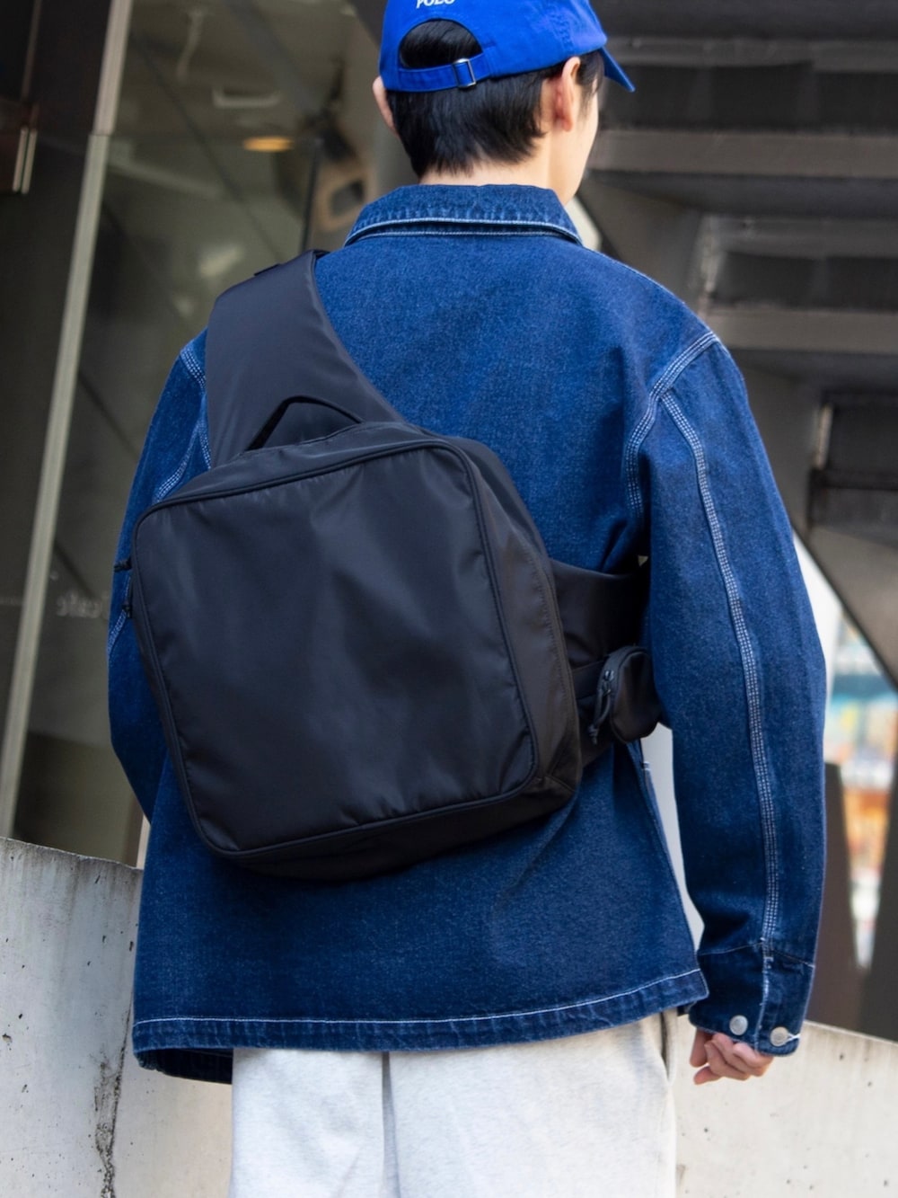 ブラック系のショルダーバッグ、ホワイト系のスウェットパンツ、ブルー系のカバーオールを着用したメンズの秋コーディネートの3枚目の写真