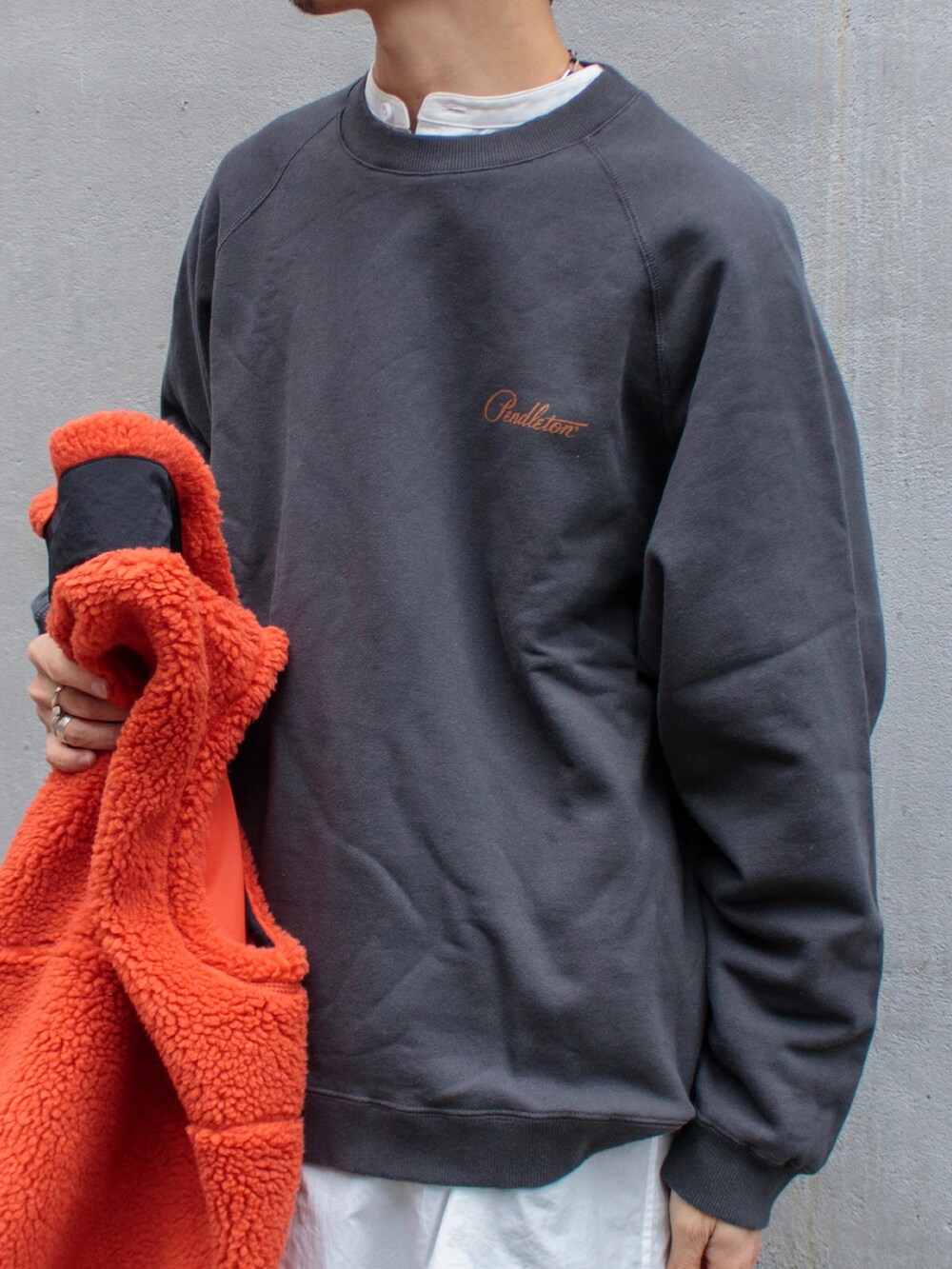 オレンジ系のベスト、グレー系のスウェット、ベージュ系のサンダルを着用したメンズの秋コーディネートの3枚目の写真