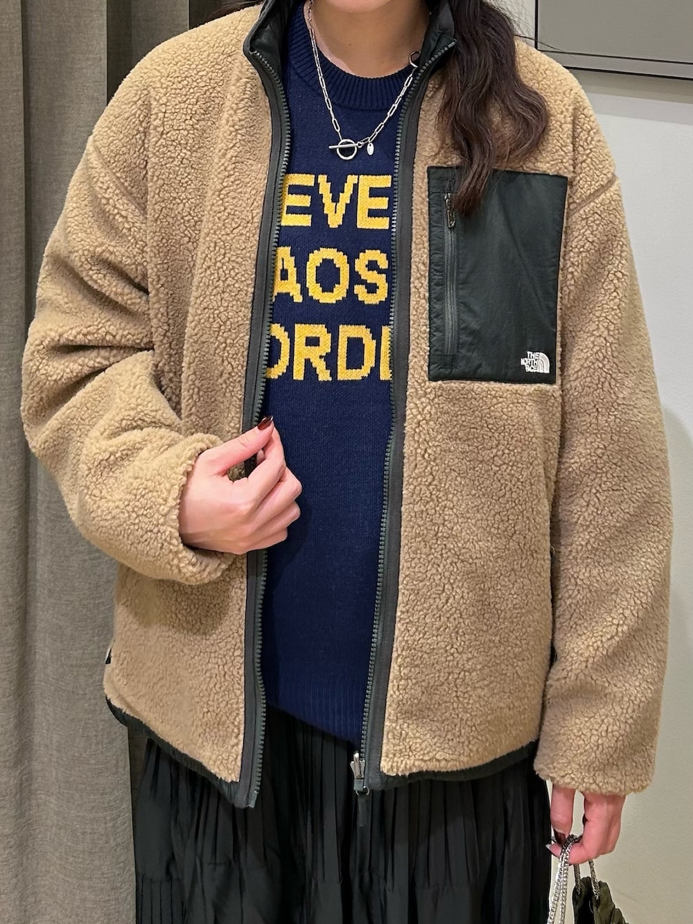 グリーン系のブルゾン、ブルー系のニット/セーター、ブラック系のスカートを着用したレディースの秋コーディネートの4枚目の写真