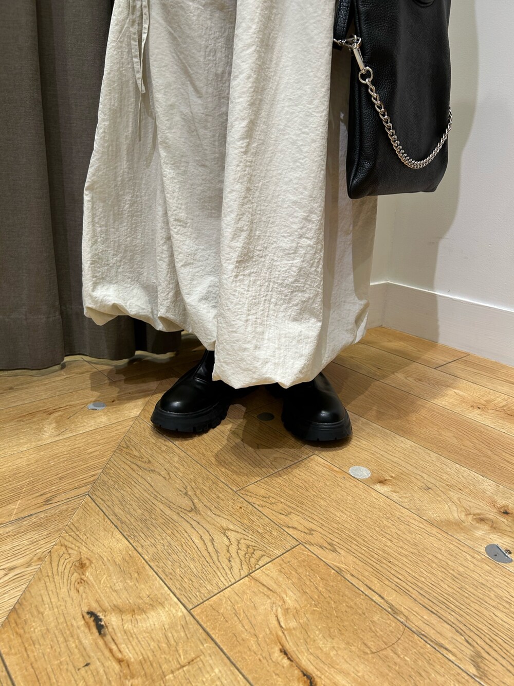 ホワイト系のスカート、ブラック系のブーツ、ベージュ系のニット/セーターを着用したレディースの秋コーディネートの5枚目の写真