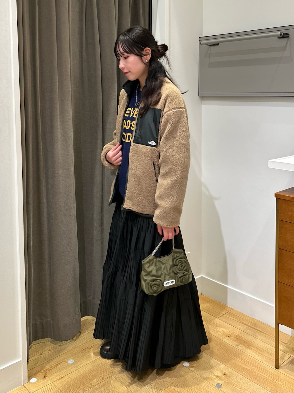 グリーン系のブルゾン、ブルー系のニット/セーター、ブラック系のスカートを着用したレディースの秋コーディネートの3枚目の写真